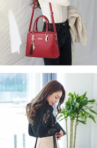 Macro detail of red faux leather tote bag with gold hardware and cat charm pendant