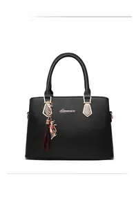 Detail of black textured leather handbag with gold Alnaoer logo and cat charm tassel