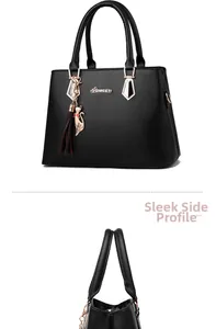 Detail view of black faux leather tote bag with gold logo and cat tassel charm