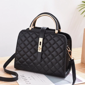 Detail of black quilted shoulder bag featuring elegant gold metal arched handles and lock
