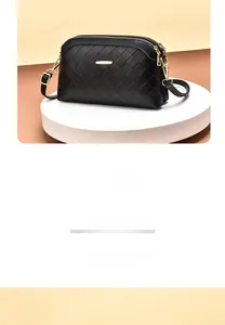 Detail of black woven texture crossbody bag with gold-tone hardware and adjustable strap