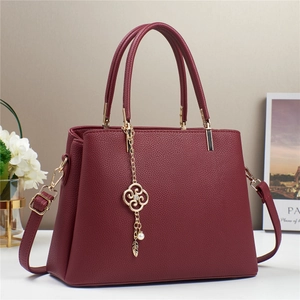 Elegante borsa a mano bordeaux in pelle con ciondolo floreale dorato e tracolla regolabile