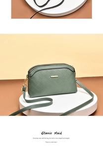 Detail of dark green quilted leather bag with dual zippers and gold hardware accents