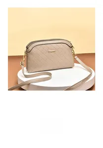 Close-up of beige quilted shoulder bag with dual gold zippers and smooth leather texture
