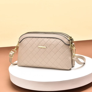 Beige quilted leather crossbody bag with three zipper compartments and adjustable strap