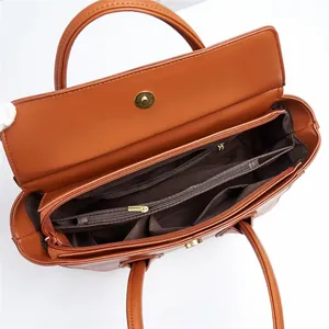 Interior detail of brown faux leather tote bag showing multi-compartment storage and gold zippers