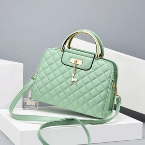 Detail of mint green quilted leather bag with gold handle and deer-shaped charm