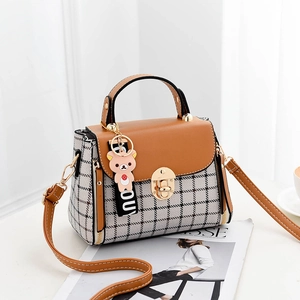Chic checkered crossbody bag with brown leather flap and bear charm accessory