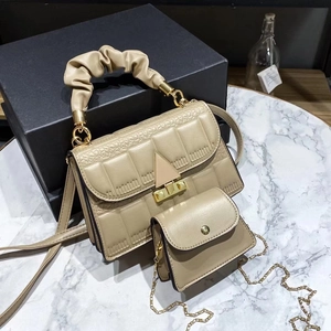 Detail of khaki textured handbag with block embossing and gold metal clasp closure