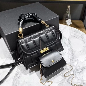 Quilted black handbag set with ruched handle and small gold chain pouch on marble