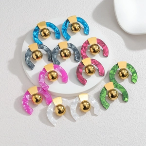 Gros plan sur des boucles d'oreilles créoles C en acrylique marbré avec détails dorés