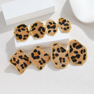 Detailed macro view of four leopard print geometric earrings with gold metal borders