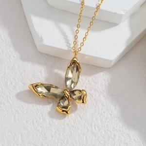 Detail showing gold butterfly necklace pendant with marquise-cut crystals on white stone stand
