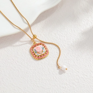 Collier doré avec pendentif rose 3D et émail magenta sur fond de pierre texturé