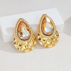 Macro detail of gold vintage earrings featuring amber pear-cut gems and textured metal