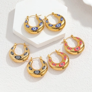 Détail de boucles d'oreilles créoles dorées en U avec breloques œil en rouge, bleu et noir