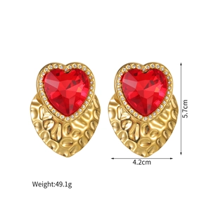 Detail view of large red heart earrings with 5.7cm size and gold hammered texture