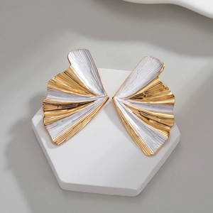 Gilded two-tone pleated fan earrings displayed on a white hexagonal display stand