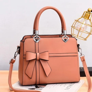 Coral orange bow textured crossbody bag with heart hardware and adjustable strap