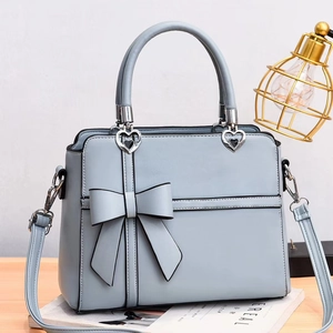 Detail of light blue bow handbag with heart charm on a minimalist wooden table