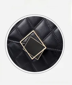 Close-up of golden geometric square clasp and quilted leather on black shoulder bag