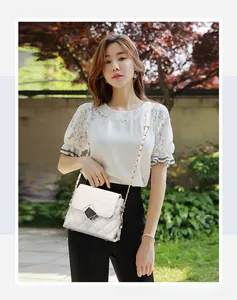 Detail of white quilted crossbody bag with gold-tone twist lock and elegant chain strap