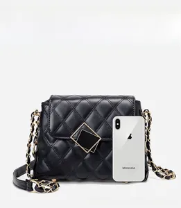 Quilted chain shoulder bag in black shown next to a smartphone for size comparison