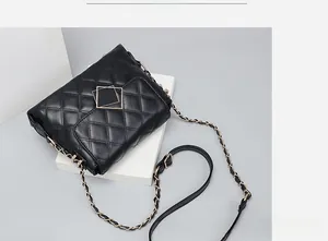 Detail of black quilted leather shoulder bag with gold metal buckle and chain strap