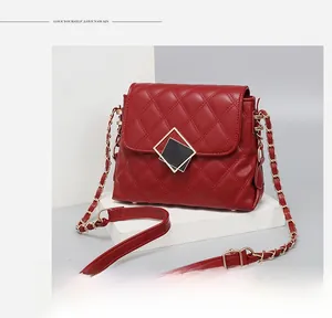 Detail of dark red quilted crossbody bag with black-gold diamond rotating lock and chain strap