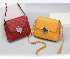 Close-up of quilted rhombic chain bags in burgundy and yellow with square metal buckles
