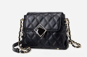 Detail of black quilted leather shoulder bag featuring golden square metal lock and chain