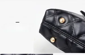 Detailed view of black quilted leather bag base with protective gold metal studs