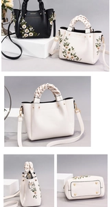 Detailed view of embroidery patterns and woven handles on a vintage style tote bag