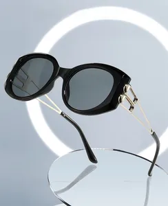 Detail of black oval sunglasses frame showing gold metal hinges and computer safety lens
