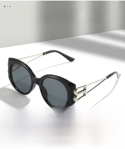 Detail showing elegant gold metal temples and cutout hinge on black oval sunglasses