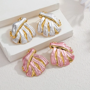 Boucles d'oreilles feuilles texturées or et argent sur un support en pierre blanche