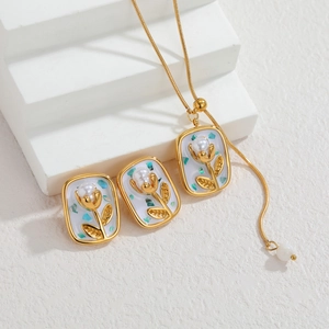 Detailed set of gold tulip necklace and earrings with pearl inlay on white square plates