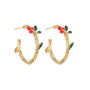 Golden C-shaped cherry earrings with branch texture and red berries on white backdrop