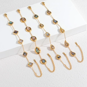 Détail de bracelets en acier doré 18k avec breloques en nacre d'abalone en forme de goutte