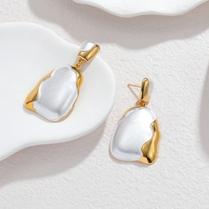 Modern 18k gold plated stainless steel asymmetric earrings on white ceramic tray