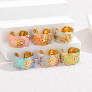 Close-up of six gold adjustable rings with colorful enamel marble texture and sunflower detail