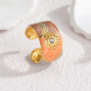 Macro detail of sunburst motif ring with orange marble enamel and white crystal inlay