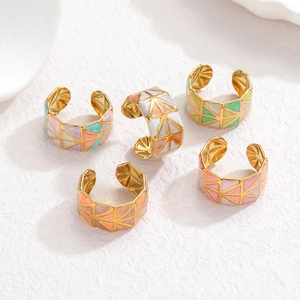 Detailed macro view of colorful geometric enamel triangles on gold plated titanium rings