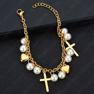 Bracelet bohème doré avec perles blanches, breloques croix et cœur sur surface noire