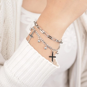 Double-layered silver cross bracelet with paperclip chain and bead charms on wrist