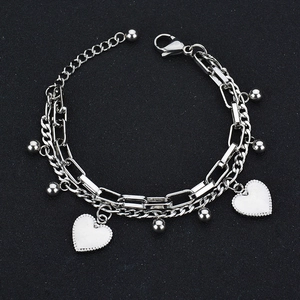 Détail de la chaîne double couche en acier argenté avec charms cœur blancs et pendentifs boules