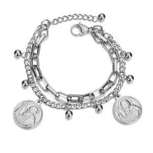 Gros plan du bracelet double chaîne argenté avec pendentifs pièces de saint et billes métal