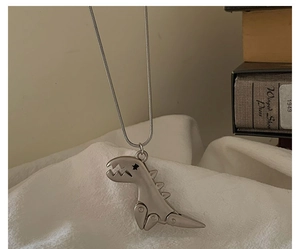 Retro mechanical dinosaur pendant necklace with silver chain on white fabric background