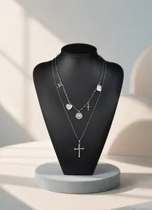 Detail of layered titanium steel necklace with heart and cross pendants on display