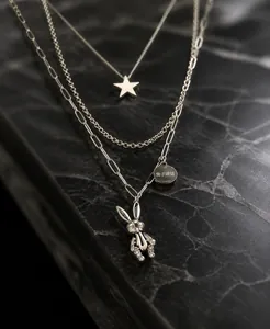 Detailed macro view of triple-layered titanium necklace with rabbit and star charms